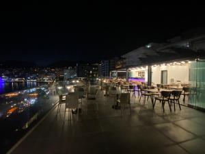 a restaurant with tables and chairs on a balcony at night at Julia Hotel in Sarandë