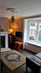 een woonkamer met een open haard en een raam bij Blue Ensign Cottage in Weymouth