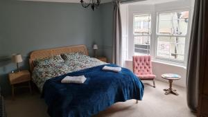 a bedroom with a bed with a blue blanket and a chair at Blue Ensign Cottage in Weymouth