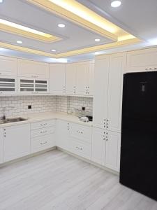 a kitchen with white cabinets and a black refrigerator at Kulaksız Köşk Villa in Rize
