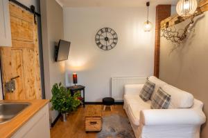 a living room with a couch and a clock on the wall at Apartamenty sudeckie nad zalewem IV in Sosnówka
