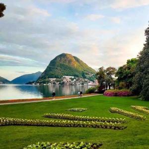 a park with a mountain and a body of water at Urban Flat in Lugano