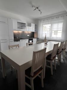 una cocina con una gran mesa blanca y sillas en Ferienwohnung zum Scheibe-See, en Hoyerswerda