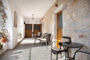 Habitación con mesas, sillas y pared de piedra. en TRADITIONAL HOUSE ALEPIS IN AREOPOLIS, en Areopoli