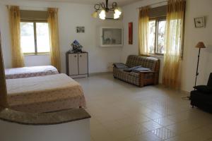 a bedroom with two beds and a couch and windows at Villa Giù, indipendent villa near airport and sea in Cinisi