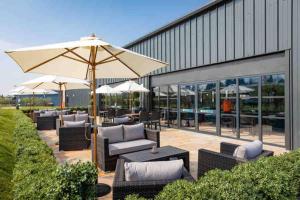 un patio con sillas, mesas y una sombrilla en Sea view deluxe lodge en Lowestoft