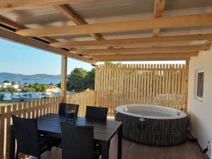 a patio with a hot tub and a table and chairs at Tiny House Lily with jacuzzi in Sveti Filip i Jakov