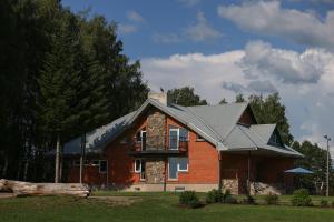 a red brick house with a gambrel roof at Kalniem Pāri Guest House in Nīgrande