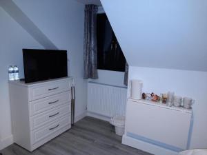 una habitación con una cómoda blanca con un televisor. en Glenbeg Lodge B&B, en Rathdrum