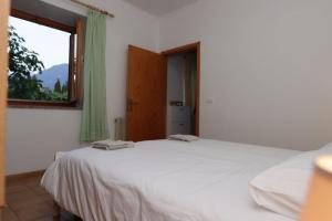 a bedroom with a white bed and a window at Appartamento Valentina in Levico Terme