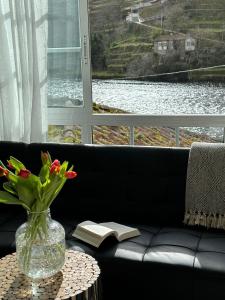 een glazen vaas met bloemen op een tafel voor een raam bij Casa Amodiño in Belesar
