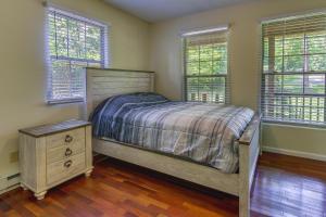 Schlafzimmer mit einem Bett, einer Kommode und Fenstern in der Unterkunft Cozy Bainbridge Retreat with Fireplace and Deck! 