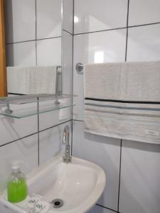 a white bathroom with a sink and towels at Estancia Aguas Brancas in Urubici