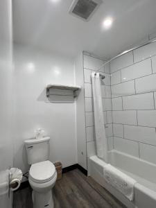 a white bathroom with a toilet and a bath tub at Sunshine Motel in Long Beach