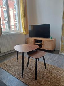 a living room with a table and a tv at La Belle Armentières, maison triplex cosy proche de Lille in Armentières +13 photos