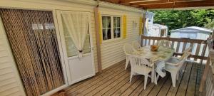 a table and chairs on a porch with a door at Bungalow dans résidence privée in Dolus-d'Oléron