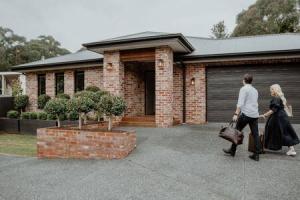 a man and a woman walking into a house at BADGER HOUSE - 4 Bed, 4 Bath, Stunning Entertainer plus Fire in Healesville
