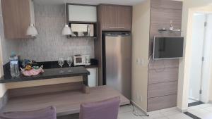 eine Küche mit einer Theke mit einem Kühlschrank und einem TV in der Unterkunft Aldeia das Aguas Village in Barra do Piraí