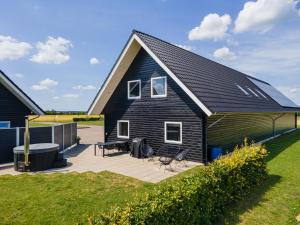a black house with a deck and a backyard at Fuglhus - hyggelig ferie på landet in Rødekro