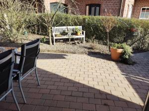 un patio con banco, mesa y sillas en FeWo Holunderbusch, en Saerbeck