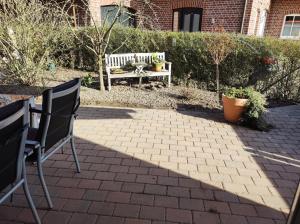 eine Terrasse mit einer Bank, einem Tisch und Stühlen in der Unterkunft FeWo Holunderbusch in Saerbeck