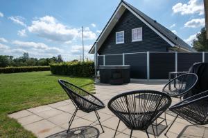 een patio met 2 stoelen en een huis bij Fuglhus - hyggelig ferie på landet in Rødekro