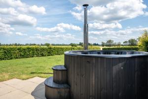 einem hölzernen Whirlpool auf einem Feld mit zwei Hockern in der Unterkunft Fuglhus - hyggelig ferie på landet in Rødekro