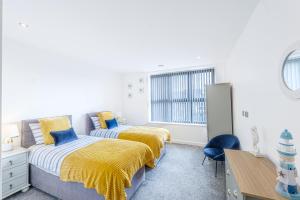 a bedroom with two beds and a desk and a window at Modern Apartments in Vibrant Ramsgate in Kent
