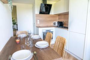 a kitchen with a wooden table with chairs and a dining room at Modern Guest -Sainte Eulalie in Sainte-Eulalie