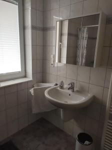 een witte badkamer met een wastafel en een spiegel bij FeWo Holunderbusch in Saerbeck