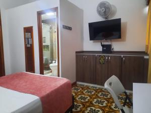 a hotel room with a bed and a flat screen tv at Hotel Boutique el Sol in Cartago