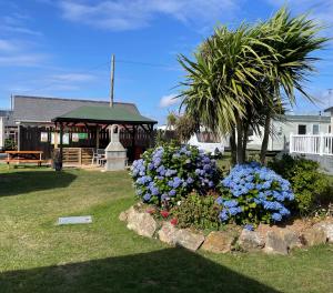 a garden with flowers in front of a gazebo at Sea Breeze in Perranporth