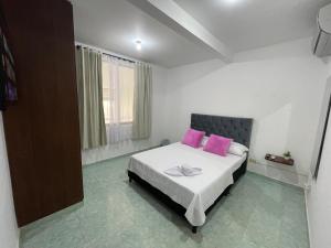 ein Schlafzimmer mit einem Bett mit zwei rosa Kissen in der Unterkunft Alojamiento Yopal in Yopal