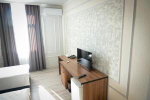 a hotel room with a bed and a television on a desk at Hotel Borjomi in Shymkent