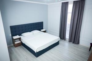 - une chambre avec un grand lit et une fenêtre dans l'établissement Hotel Borjomi, à Chimkent