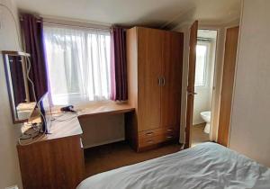 a bedroom with a desk with a computer and a bed at Bordeaux - Church Farm in Pagham