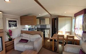 a living room and kitchen with a couch and a table at Bordeaux - Church Farm in Pagham +8 photos