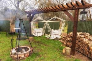 un patio trasero con 2 sillas blancas y una hoguera en Homestead Hut 