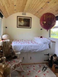 ein Schlafzimmer mit einem Bett, einem Ballon und einem Stuhl in der Unterkunft Homestead Hut 