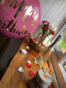 a table with a happy birthday balloon and flowers on it at Homestead Hut 