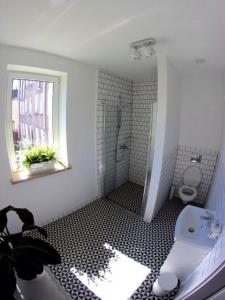 a white bathroom with a shower and a toilet at SPOKO Hostel in Gdańsk