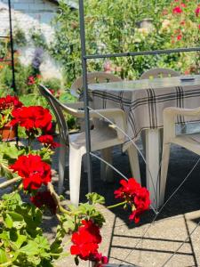 einen Tisch, Stühle und rote Blumen auf der Terrasse in der Unterkunft Gjorgji Apartments 68a in Ohrid