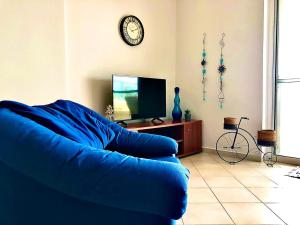sala de estar con sofá azul y TV en ΑquaView, en Gythio