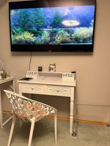 a tv hanging on a wall with a white desk at Zimmer zum Wohlfühlen in Eching