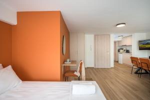 1 dormitorio con pared de color naranja, mesa y sillas en Senaon Urban Living, en Heraclión