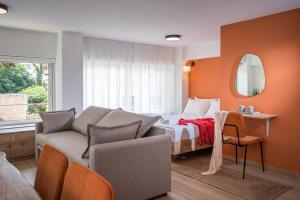 1 dormitorio con cama, sofá y espejo en Senaon Urban Living, en Heraclión
