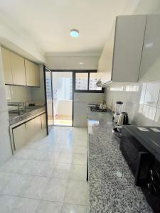 a large kitchen with white cabinets and a tile floor at Appartement En Bord de Mer in Tangier