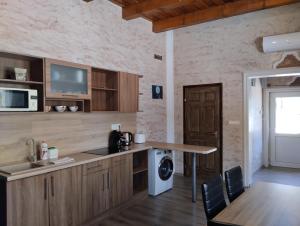 a kitchen with wooden cabinets and a table and a microwave at Pipacs Apartman in Nyíregyháza