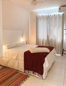 um quarto branco com uma cama grande e uma janela em Residencial COLIBRI em Garopaba