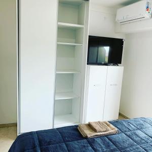 a bedroom with a bed and a tv and shelves at Entre Ríos Alquileres Temporarios. in Paraná